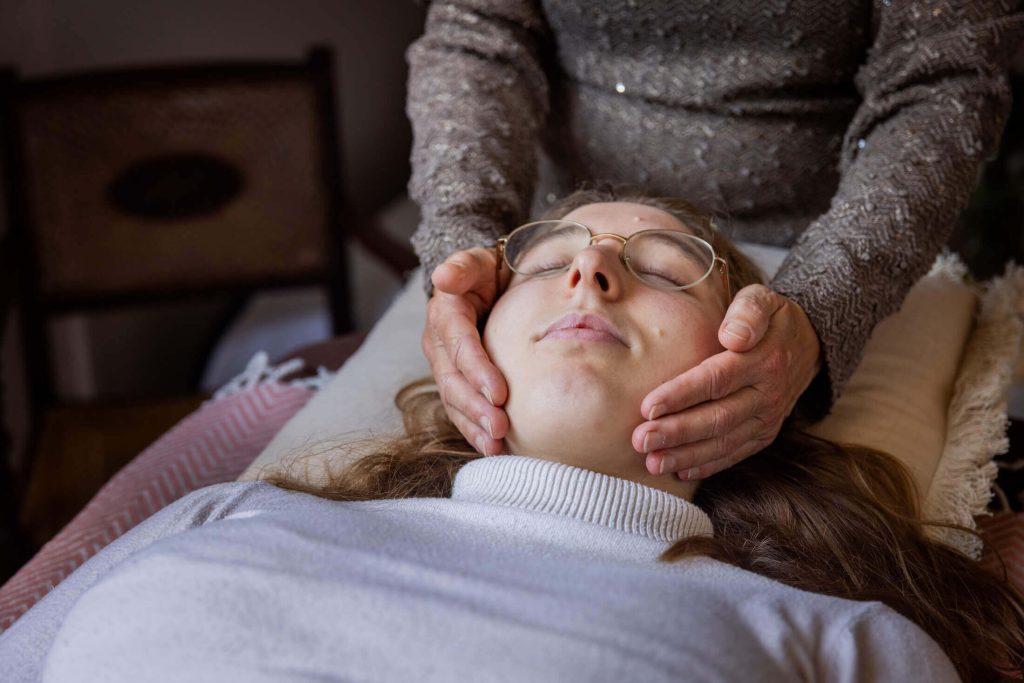Handen rondom het gezicht van de client op de behandeltafel. praktijk voor healing touch